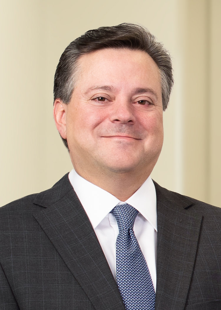 close up professional shot of Craig Parker standing in a bright office wearing a black suit and blue tie